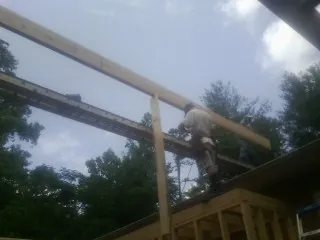 Carpenter setting a ridge beam over a new addition frame — Ice Dam Removal by Roofing Brothers in Eastport