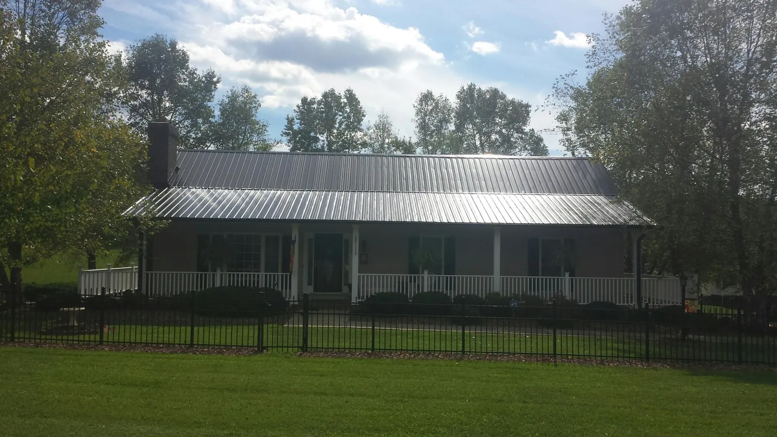 Gray metal roof on a brick ranch with a full width front porch — Gutter Guard Installation work by our crew in Eastport