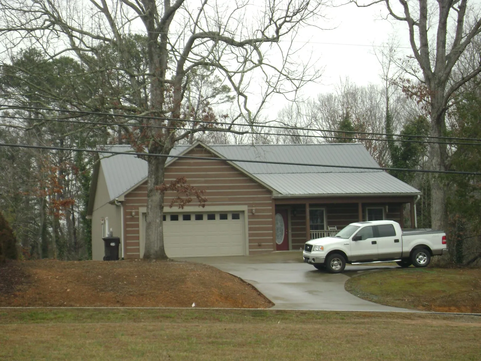 Gray metal roof on a log sided house with an attached two car garage in Eastport