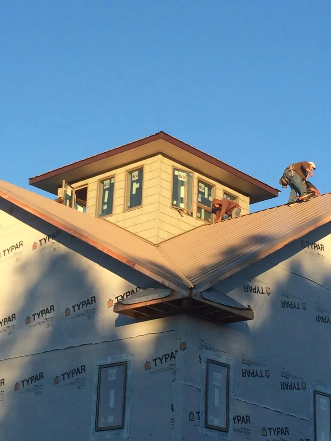 Roofers working around a rooftop cupola on a new metal roof at sunset — Roof Waterproofing in Eastport by Roofing Brothers